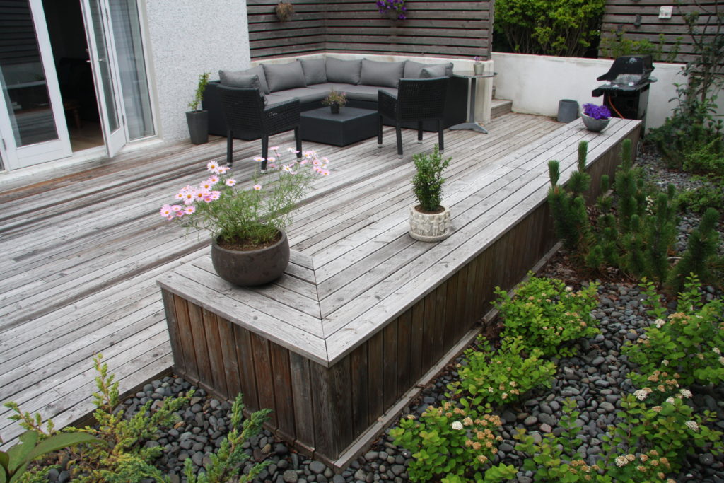 Foreground with an informal bench and a background with an outdoor sofa and a sheltering wall